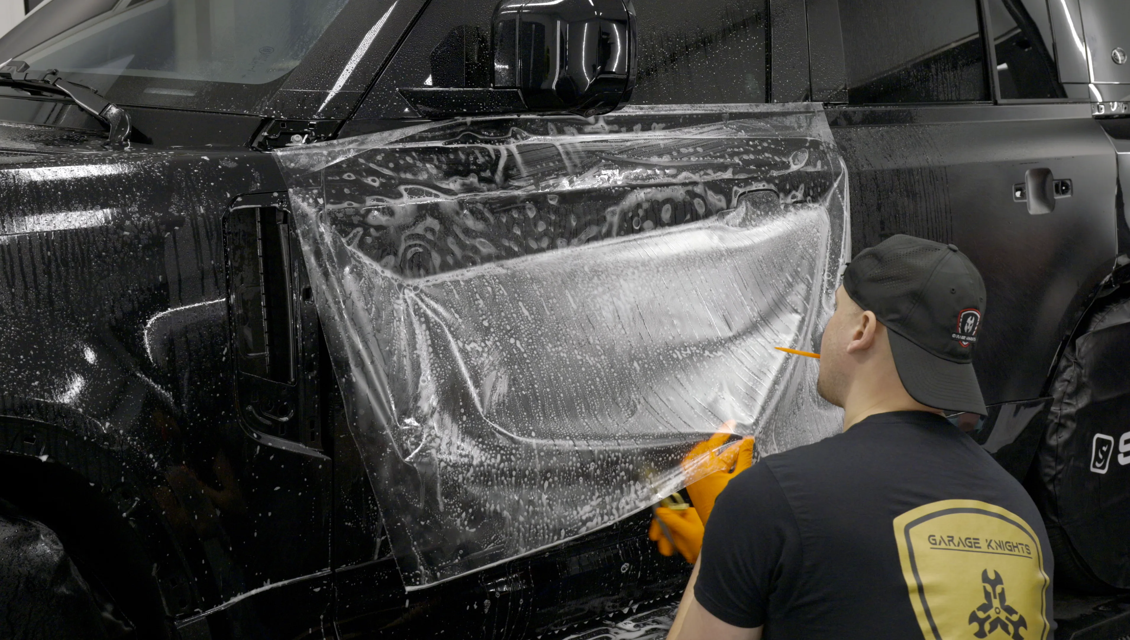 Kamil Matynia installing paint protection film on a vehicle door at Garage Knights Ottawa