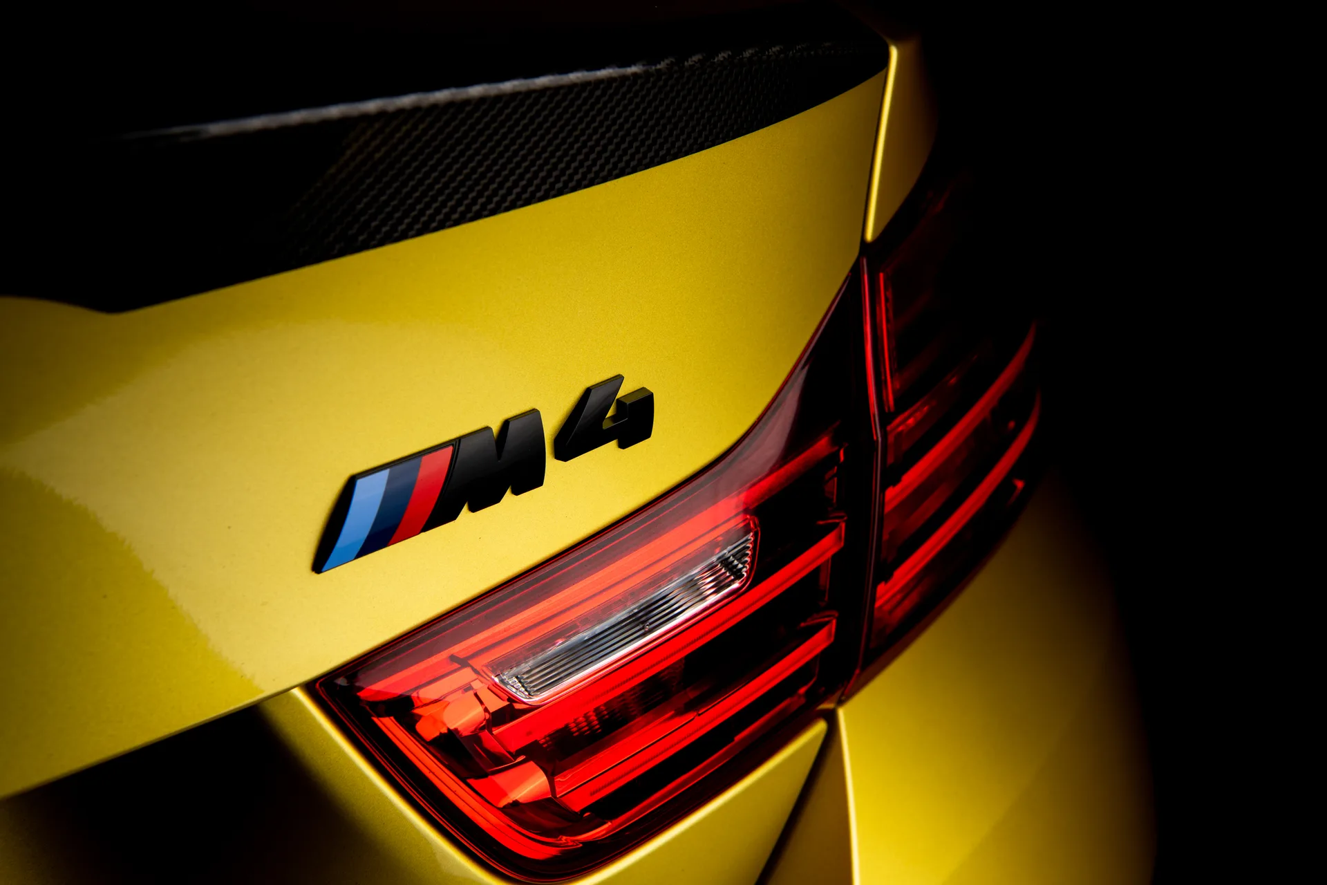 Gold metallic colour change wrap on a BMW M4 rear — M4 badge and carbon fibre spoiler detail at Garage Knights Ottawa