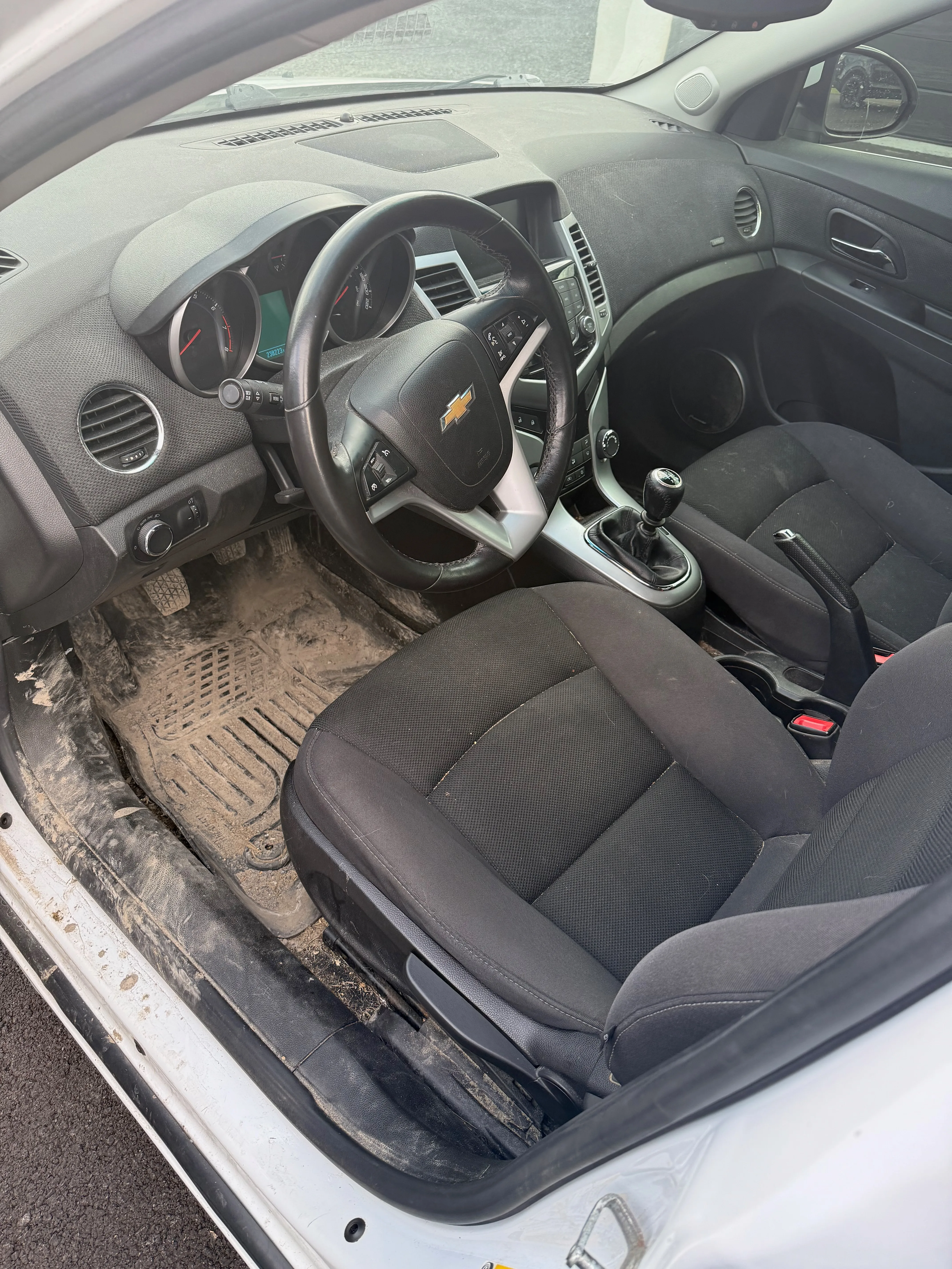 Interior detailing before — driver side with soiled floor mats and dirty dashboard