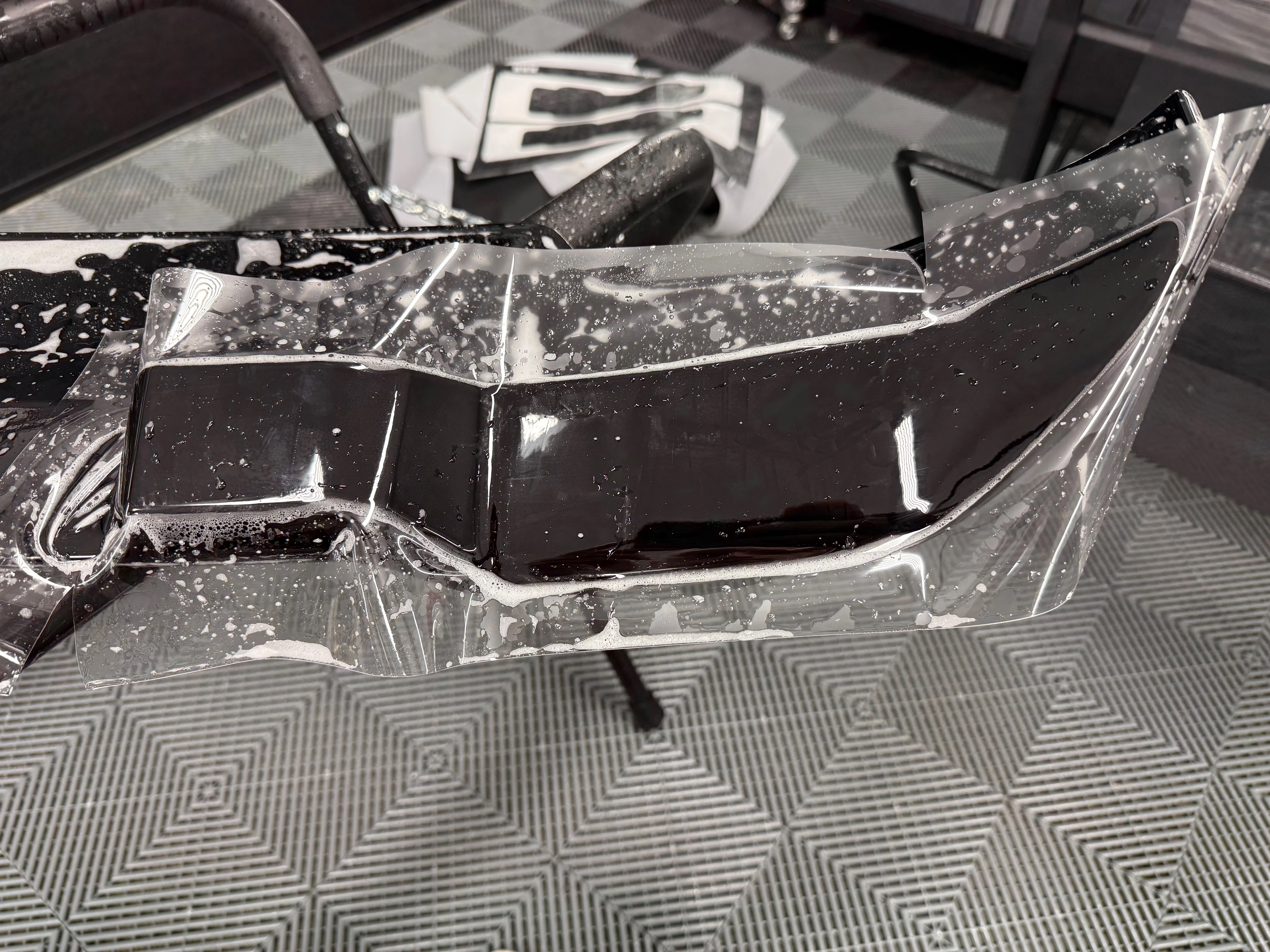 Rear spoiler being wrapped with PPF on a stand — component-level installation for full coverage