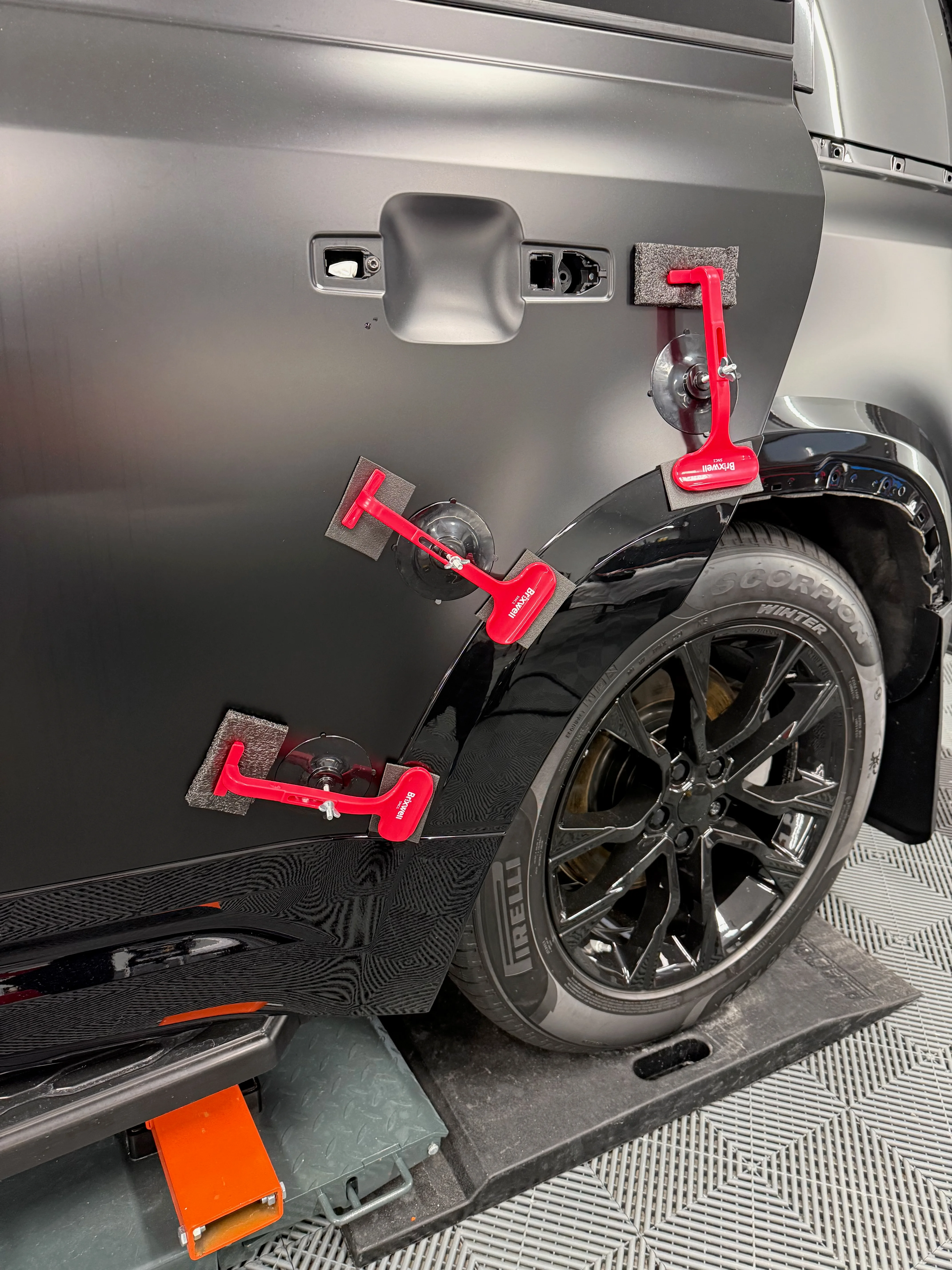 Wide arch extension installation on Land Rover Defender rear fender — clamped for alignment before bonding